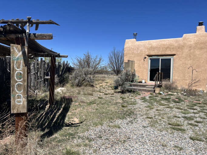 Adobe-style retreat nestled in desert landscape with rustic entrance gate marking your arrival to this peaceful southwestern getaway.