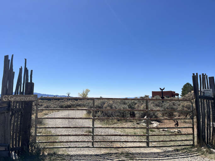 Property entrance gate opens to desert landscapes and mountain views under endless blue skies.