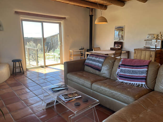 Relax in your rustic living space with exposed beams, cozy leather seating, and garden views through sunny windows.