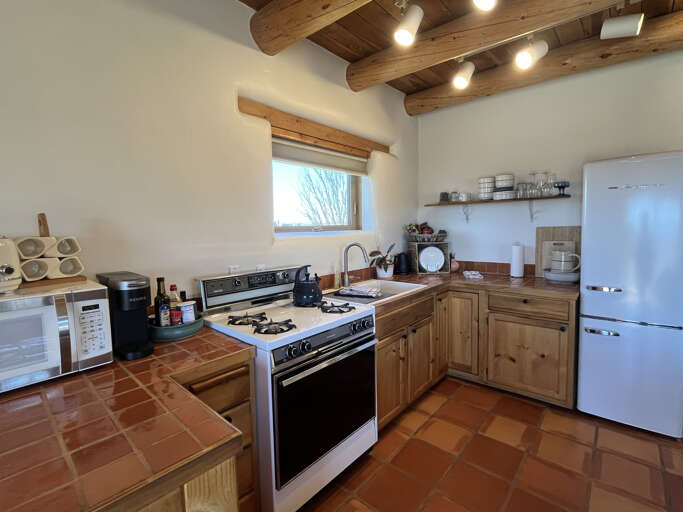 Your rustic kitchen blends modern conveniences with charming exposed beams and warm terra cotta floors for authentic cooking experiences.