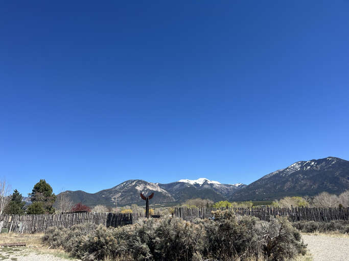 Stunning mountain landscape with snow-capped peaks under brilliant blue skies surrounds this peaceful rural property location.