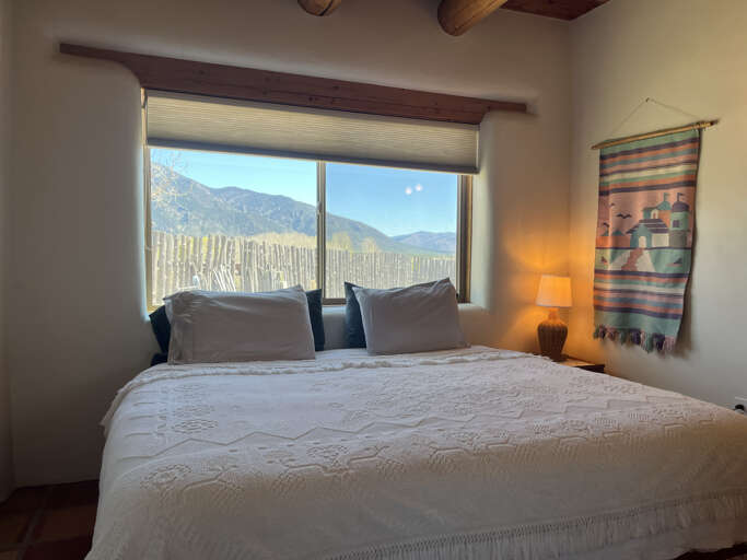 Wake up to stunning mountain views through your bedroom window, where rustic beams and warm lighting create a peaceful retreat.
