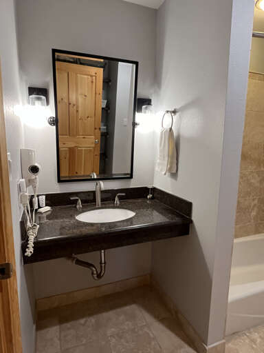 Freshen up at your own modern vanity with elegant granite countertops, wall-mounted design, and thoughtful touches like a hair dryer and fresh towels waiting for you.