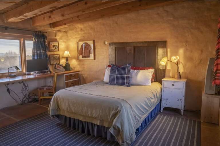 Settle into your cozy adobe-style bedroom where rustic charm meets comfort. Exposed beams, warm earth-toned walls, and thoughtful touches like plaid accents create your perfect southwestern retreat.