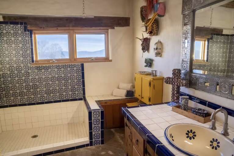 Step into this spacious bathroom with a walk-in shower featuring striking blue-and-white tilework. Handcrafted decorative masks bring cultural character to your private oasis.