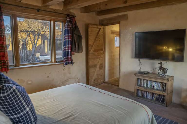 Unwind in your cozy bedroom with rustic exposed beams, a flat-screen TV, and a peek of autumn trees through your windowâyour peaceful retreat awaits.