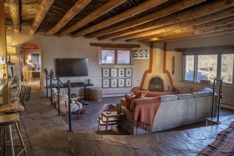 Unwind in this inviting living space featuring a cozy kiva fireplace, exposed beam ceilings, and southwestern charm. Your perfect retreat blends rustic character with modern comfort, ideal for relaxing evenings.