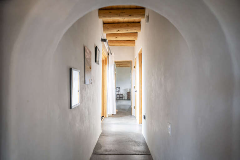 Elegant archway frames your private hallway, where rustic wood beams meet minimalist design and soft natural light guides you through this sweet retreat.