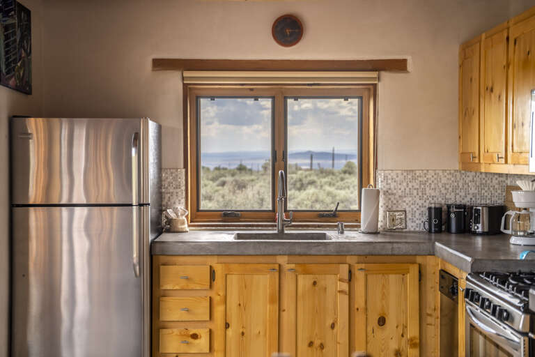 Prepare your favorite meals with stunning high-desert views as your backdrop. The fully equipped kitchen features stainless steel appliances, rustic pine cabinetry, and panoramic windows overlooking native sagebrush and distant mountains.