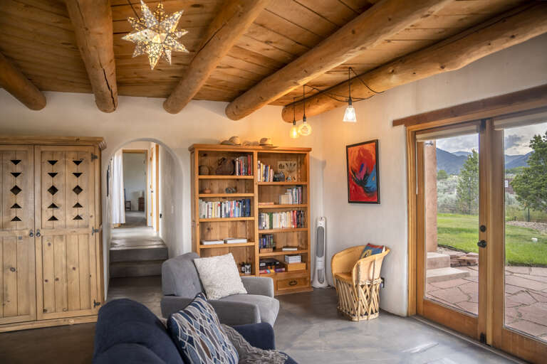 Settle into your cozy reading nook under rustic timber beams, where peaceful mountain vistas greet you through the glass door and warm natural light fills your retreat.