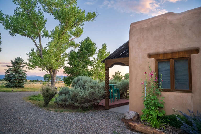 Charming adobe-style retreat set on peaceful grounds with tall cottonwoods and native landscaping. The property blends Southwestern architecture with mountain views and wide-open skies.