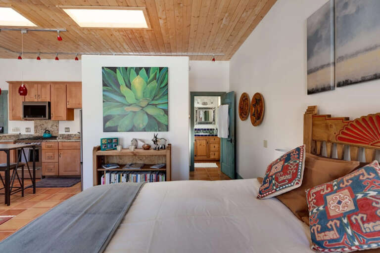 Relax in your bright, open bedroom with soaring wood ceilings and a skylight that fills the space with natural light. The cozy bed and Southwest-inspired decor welcome you into a warm, artistic retreat.