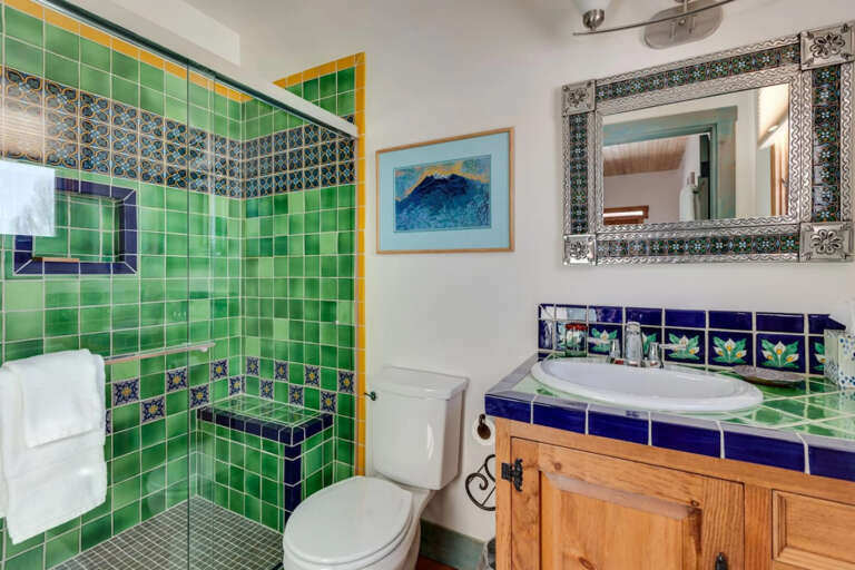 Step into your private bathroom where vibrant Mexican tiles in emerald and cobalt create an artful retreat. The spacious walk-in shower and hand-painted details add authentic charm to your daily routine.