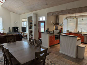 Gather around the spacious dining table and enjoy ocean breezes drifting through your fully equipped kitchen. Natural light pours in through large windows while rustic wood ceilings add warmth to your coastal retreat.