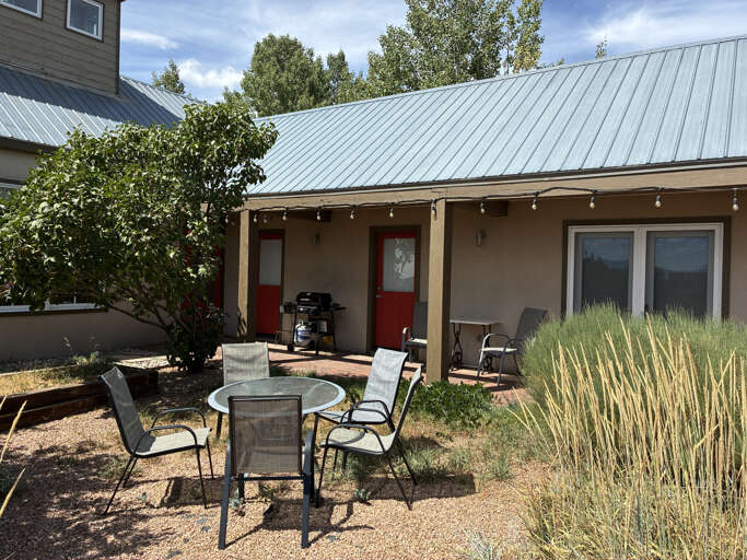 Inviting outdoor retreat featuring a covered patio with string lights, comfortable seating, and a BBQ grill—perfect for your morning coffee or evening gatherings under the open sky.
