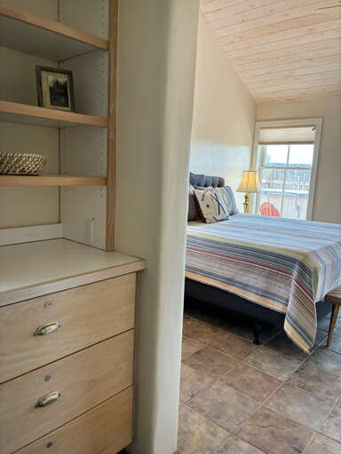 Unwind in your serene coastal bedroom with custom built-ins, tile flooring, and natural light streaming through the window.