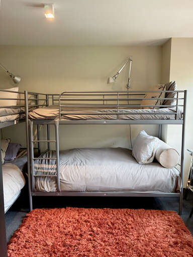 Your group will love this cozy bunk room, where everyone gets their own comfortable sleeping space. The soft rug and thoughtful lighting create a warm retreat after a day of adventure.