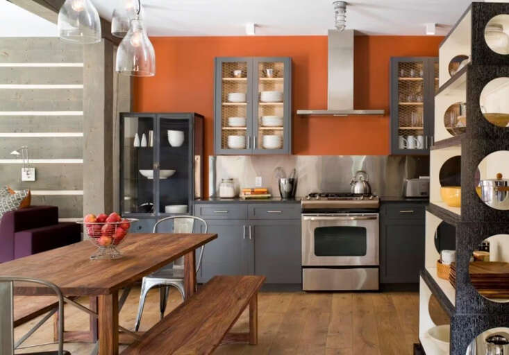 Gather around this warm, modern kitchen where your culinary adventures begin. The bold orange accent wall and sleek gray cabinetry create an inviting space to cook, dine, and make memories together.