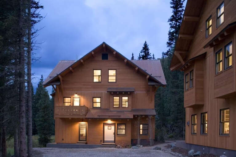 Nestled among towering pines, this mountain lodge welcomes you with warm, glowing windows at twilight. The rustic exterior and charming balconies set the stage for your peaceful alpine escape.