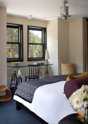 Unwind in your cozy retreat with a work-ready desk by windows framing serene forest views. Fresh flowers and plush bedding invite you to relax and recharge.