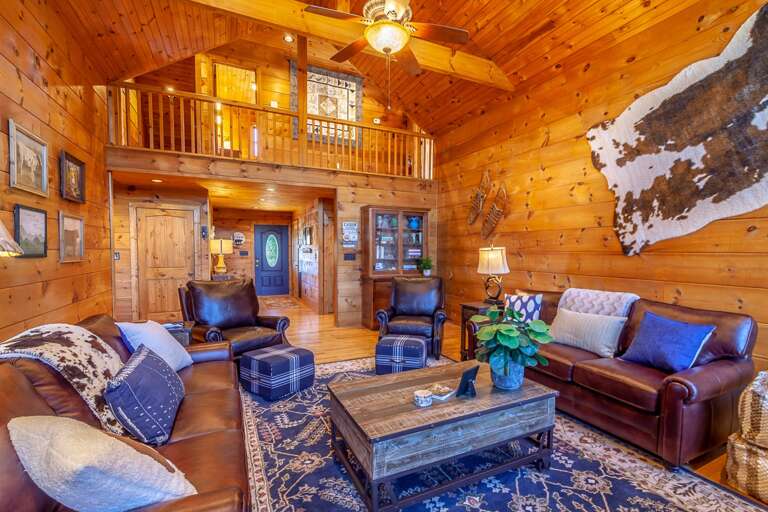 Great Room with Leather Furniture and Soaring Vaulted Ceilings, Wood Walls, and Wood Floors