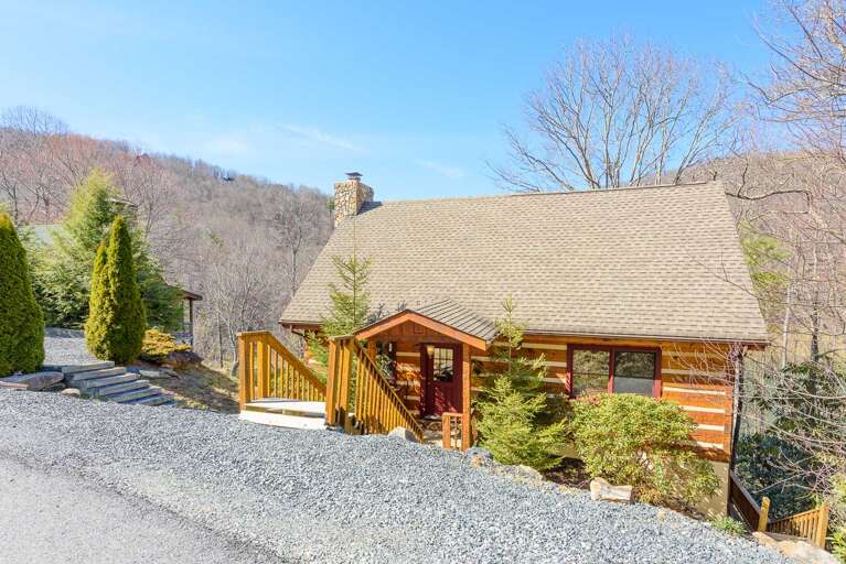 Cabin set Down off of Quiet Road with Mountaintops in Background