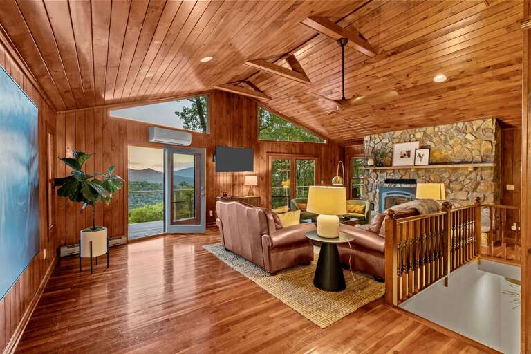 Main Living Area Features Large TV, Floor-to-Ceiling Stone Fireplace, and Deck Access