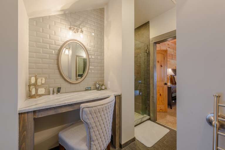 Private Ensuite Master Bathroom with Make Up Station and Tufted Chair, and Tile Shower with Frameless Glass Door