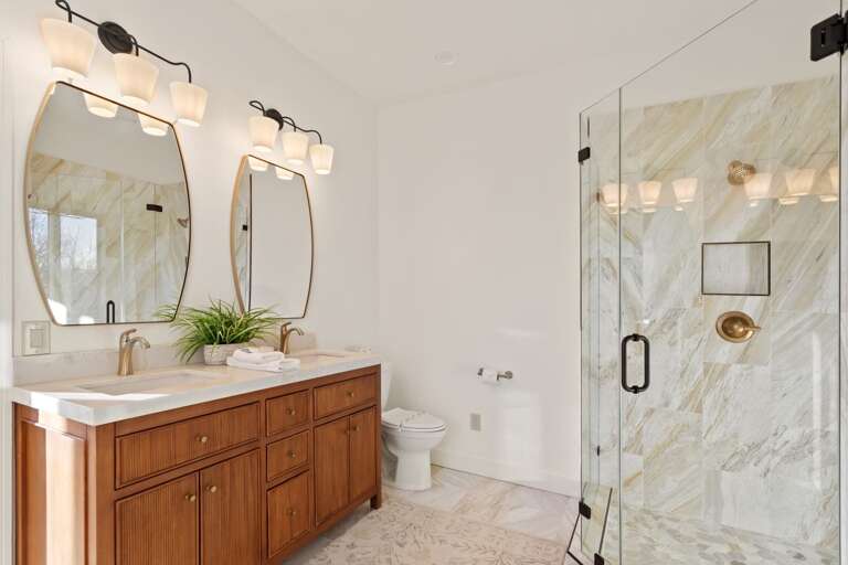 'Her' Bathroom has a Large Tile Shower with Frameless Glass Doors and a Double Sink Vanity