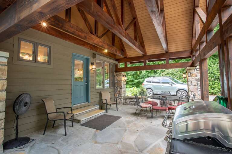 Covered outdoor flagstone patio with grill and dining.