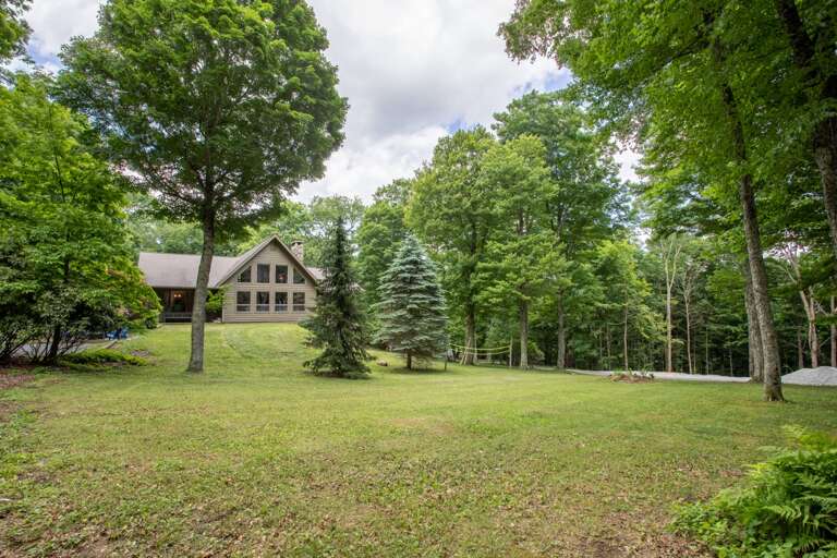 House sits on a very large yard with lots of grass and mature trees