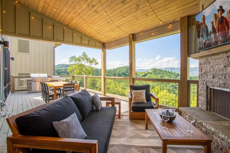 Covered Outdoor Space with Stacked Stone Wood Burning Fireplace, TV, and Edison String Accent Lighting Covered Outdoor Space with Stacked Stone Wood Burning Fireplace, TV, and Edison String Accent Lighting