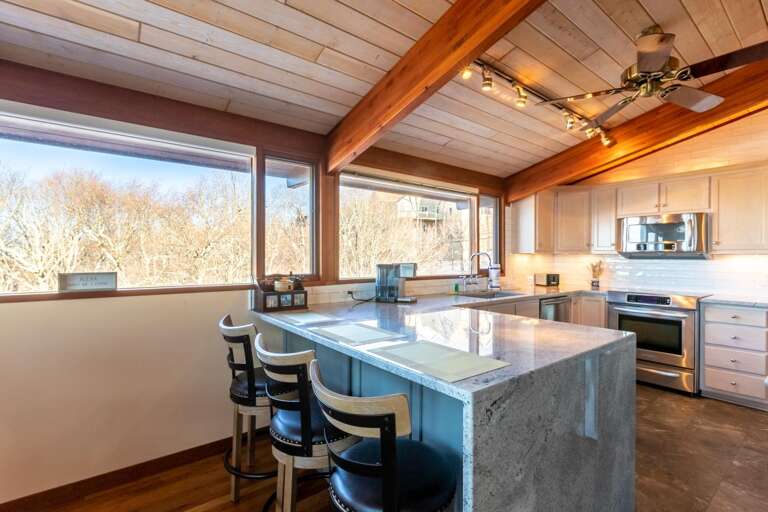 Spacious Kitchen With Sleek Surfaces And Sunlight Streaming Through Big Windows