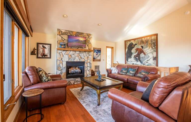 Bright Beams Bounce Around A Serene Vacation Rental Living Space With Leather Loungers And A Lit Fireplace