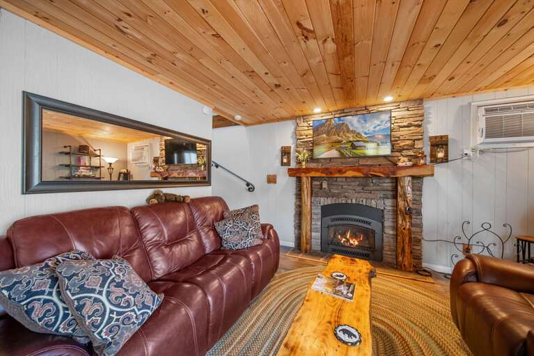 Stacked Stone Gas Fireplace. Leather Sofa and Mounted TV in the Living Room