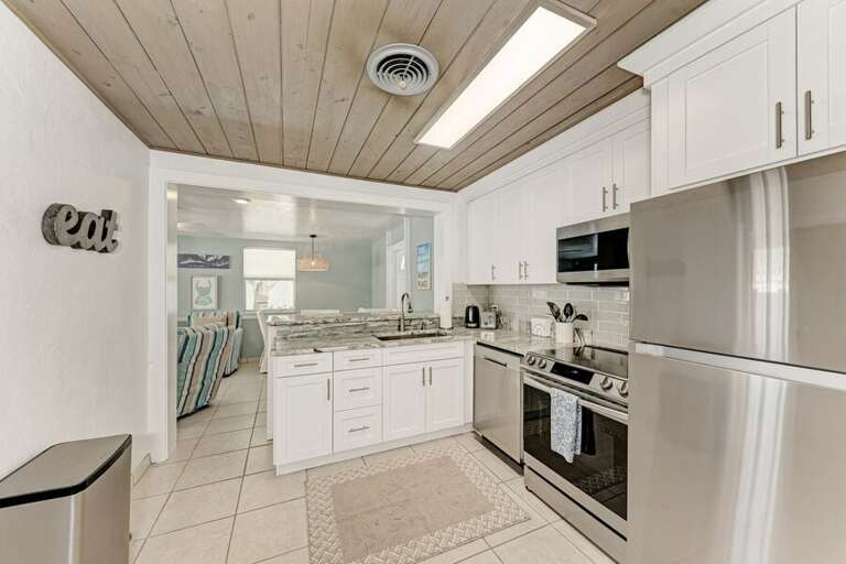 White-walled Kitchen With Wooden Ceiling And Stainless Steel Appliances White-walled Kitchen With Wooden Ceiling And Stainless Steel Appliances