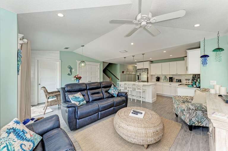 Bright Beach-theme Living Space With Sea-green Walls, Navy Sofas, And A Spacious Kitchen Area