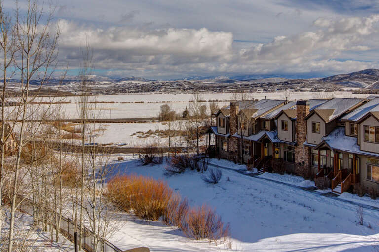 Snow-dusted townhomes nestled among winter fields and distant mountain ranges, offering a peaceful countryside retreat with scenic seasonal surroundings.