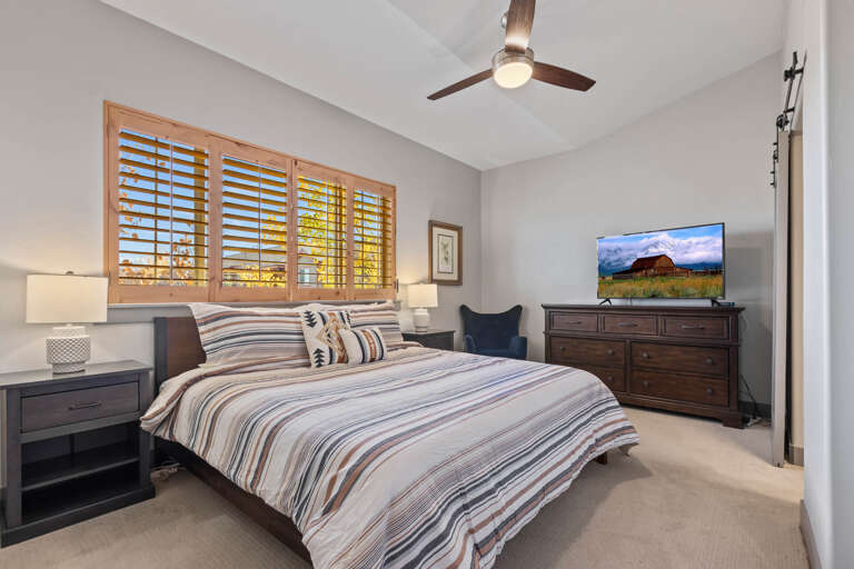 Primary Bedroom: King-sized bed, ceiling fan, TV, and comfortable bedding.