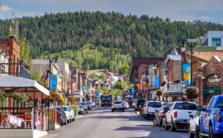 A vibrant mountain town with colorful storefronts and tree-covered slopes, offering easy access to local shops, dining, and outdoor activities in the surrounding area.