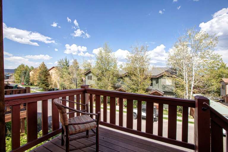 Private balcony overlooks a quiet residential neighborhood framed by aspen trees and mountain homes, offering peaceful alpine scenery during your stay.