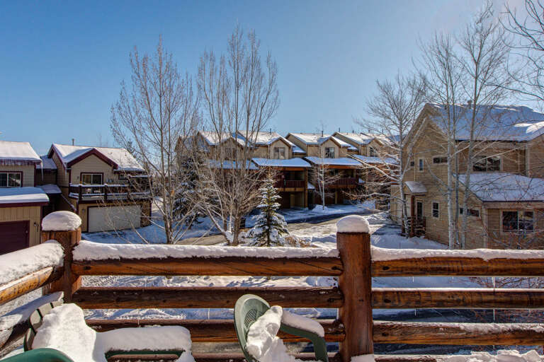 Quiet residential neighborhood nestled in a winter mountain setting, with snow-dusted rooftops and towering peaks creating a serene alpine backdrop during the colder season.