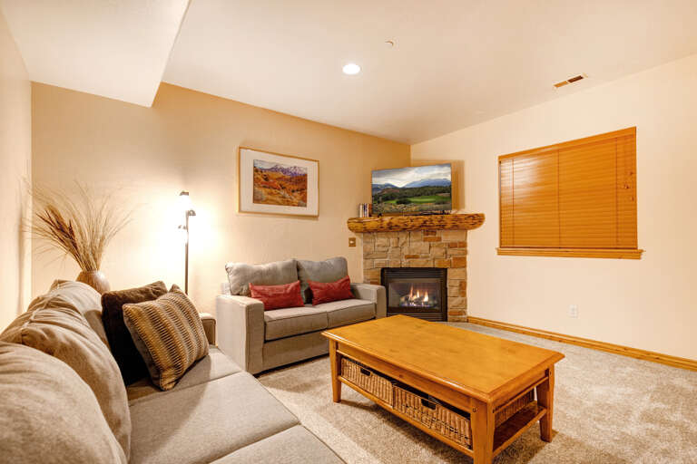 Unwind on plush sofas by your stone fireplace, perfect for cozy evenings. The bright space offers natural light and a flat-screen TV for relaxation.