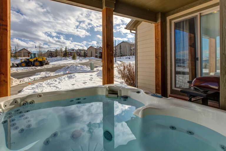 Soak in your private hot tub on the covered terrace while admiring peaceful neighborhood views and winter skies—a relaxing escape after a day exploring the slopes.