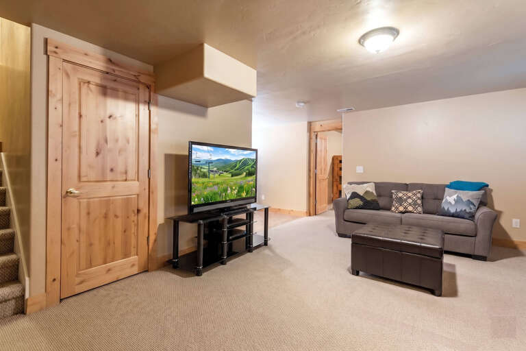 Relax in your spacious lower-level living area with a comfy sofa, large flatscreen TV, and warm wood accents. Perfect for unwinding after a day of exploring the mountains.