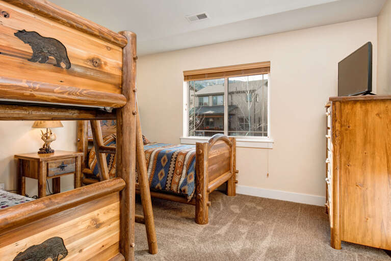 Rustic log bunk beds with bear-carved details invite your family to settle into this cozy mountain retreat, complete with charming wood furnishings and a flat-screen TV for your entertainment.