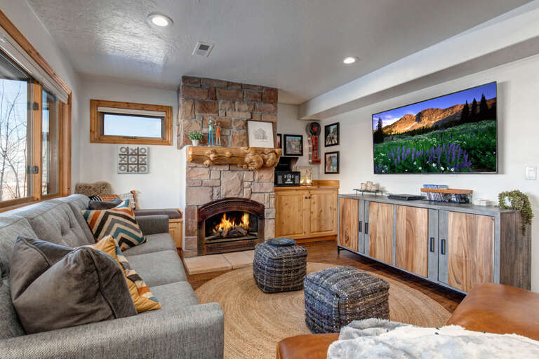 Settle into this inviting living space where a crackling stone fireplace warms your evenings. Plush seating and rustic wood details create a cozy mountain retreat vibe.