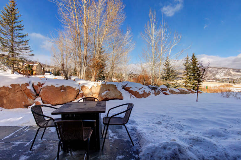 Private patio with mountain views, featuring outdoor dining space surrounded by natural rock formations and snow-dusted landscape in a serene winter setting.