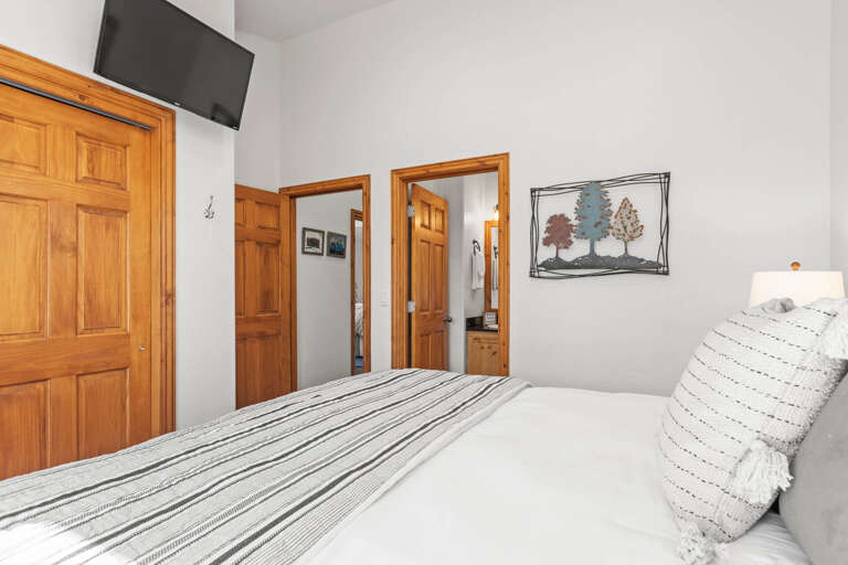Sink into crisp linens and plush pillows after a day of adventure. Your restful retreat features warm wood accents, a wall-mounted TV for cozy nights in, and charming mountain-inspired décor.