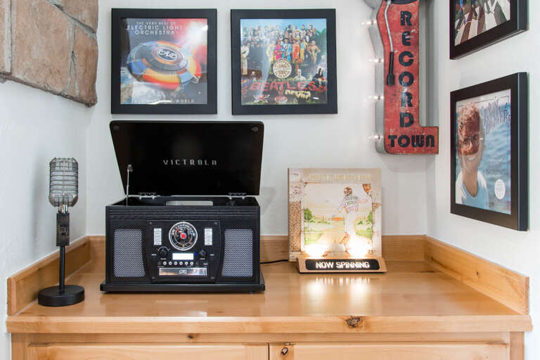 Spin your favorite vinyl records on the vintage-style turntable, displayed with classic album art and nostalgic décor for a truly timeless experience.